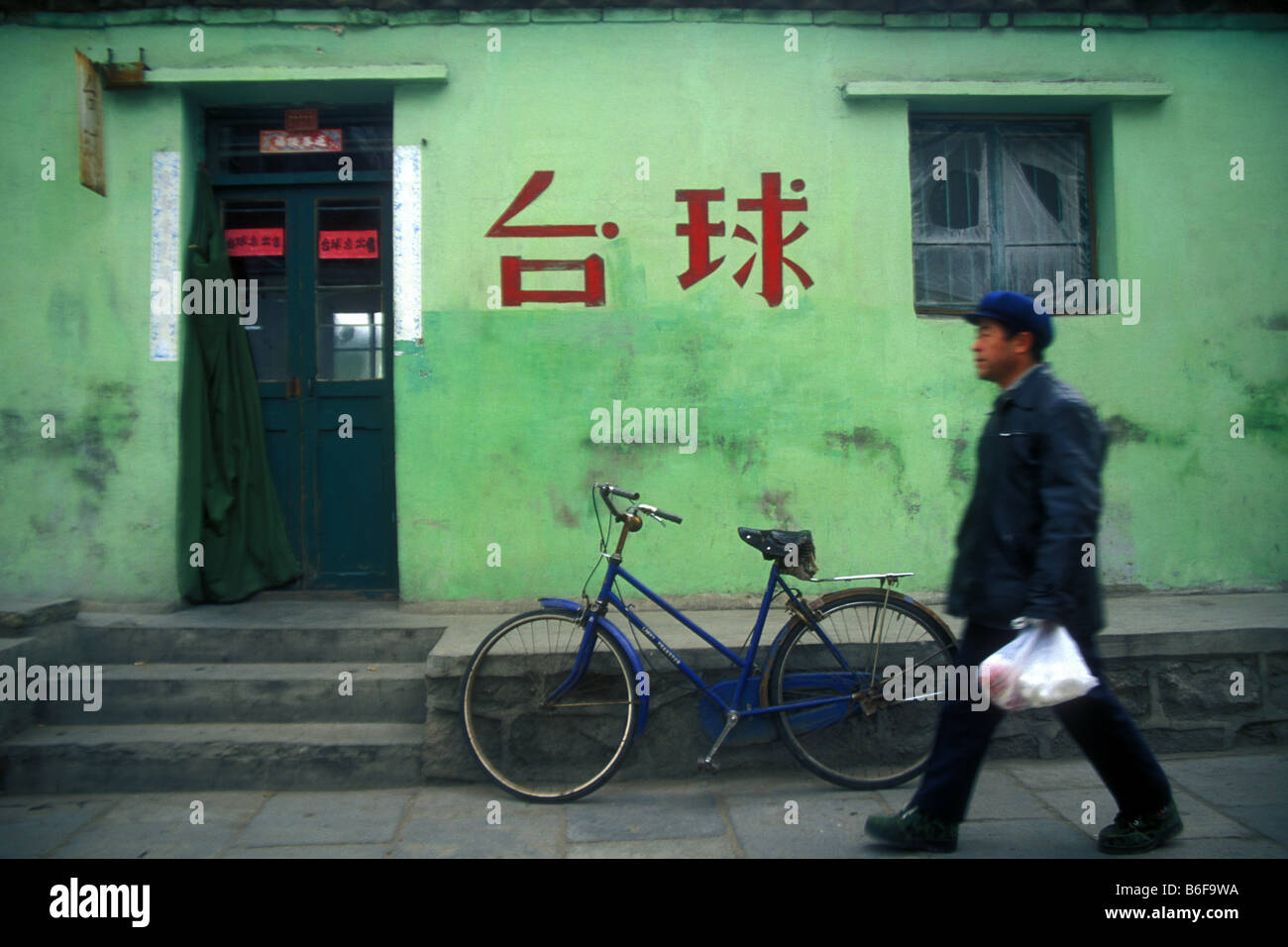 L'homme en passant un bâtiment peint en vert et en bicyce Shanhaiguan Chine Banque D'Images