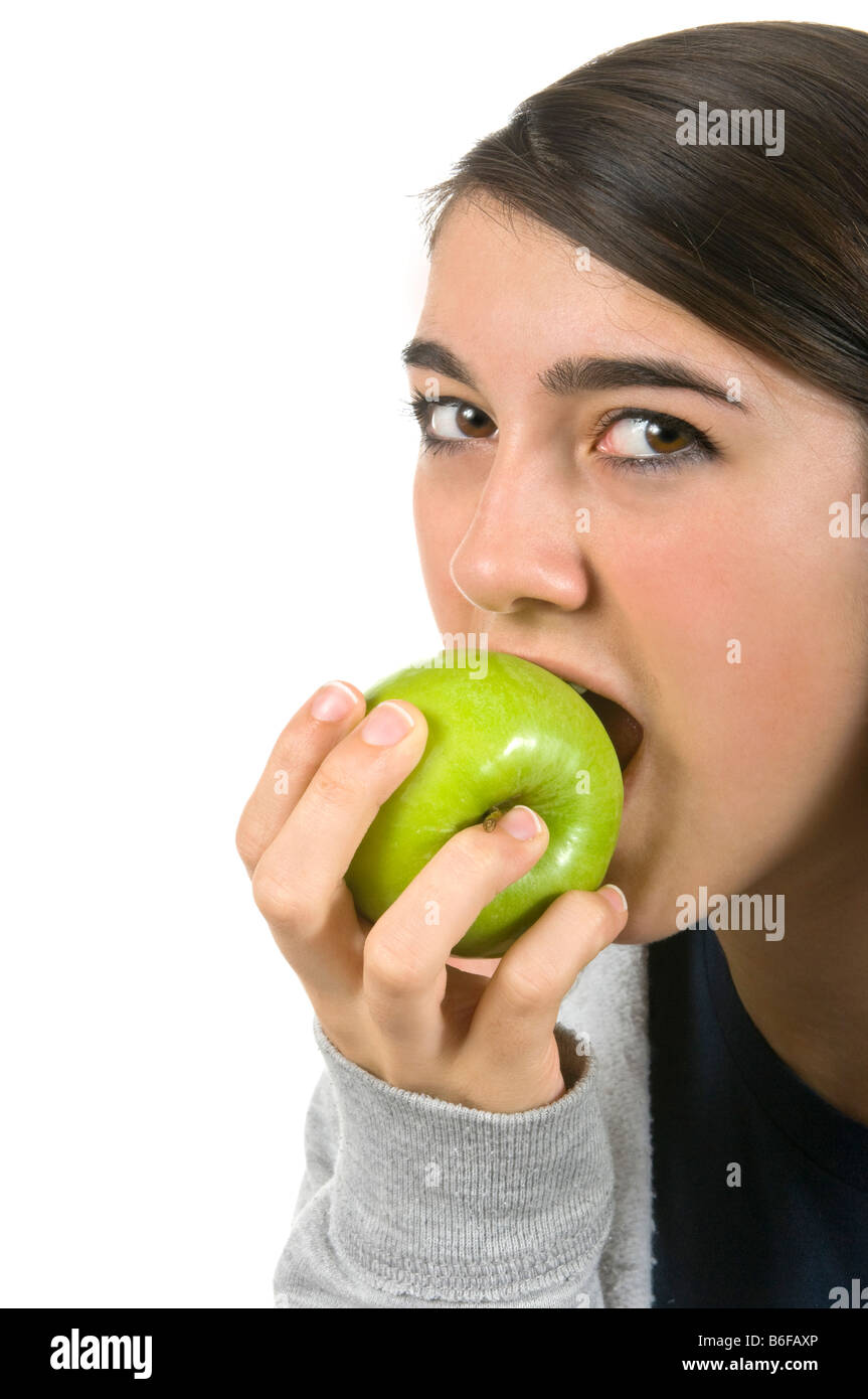 Close up portrait of vertical d'un séduisant jeune teenage girl eating a green juteuse Granny Smith Apple sur un fond blanc. Banque D'Images