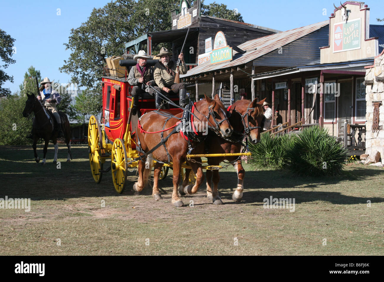 Deux cowboys conduisant le Butterfield Overland Stage Coach à travers une vieille ville de l'ouest Banque D'Images