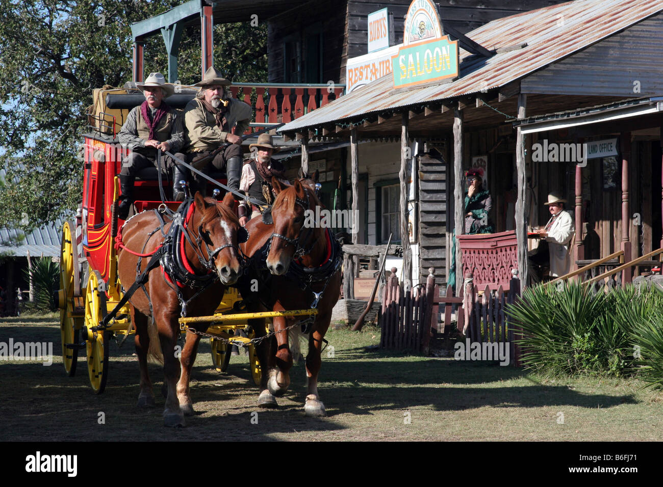 Deux cowboys conduisant le Butterfield Overland Stage Coach à travers une vieille ville de l'ouest Banque D'Images