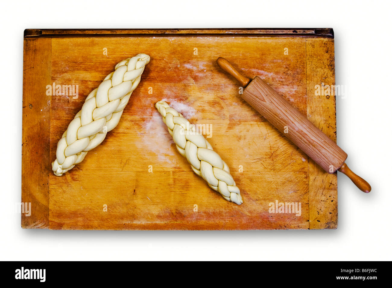 Pain tressé tressés ou non cuits, pain, sur une plaque de cuisson à côté d'un rouleau à pâtisserie Banque D'Images