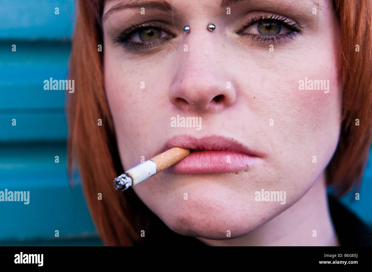 Peau pâle aux cheveux rouge jeune fille femme irlandaise avec une cigarette dans sa bouche à la moody sensuel fixant avant UK Banque D'Images