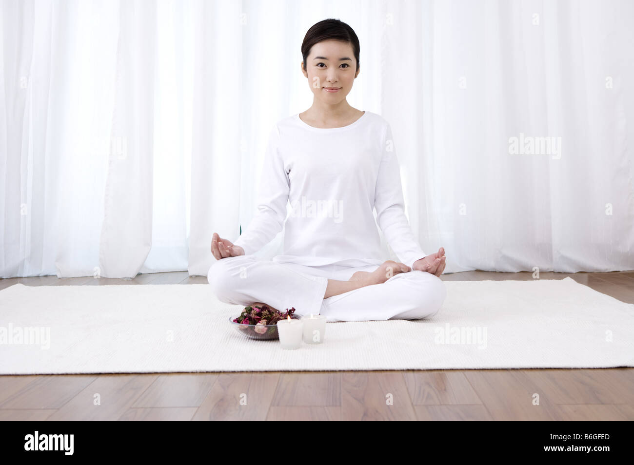 Jeune femme en position du lotus cross legged smiling Banque D'Images