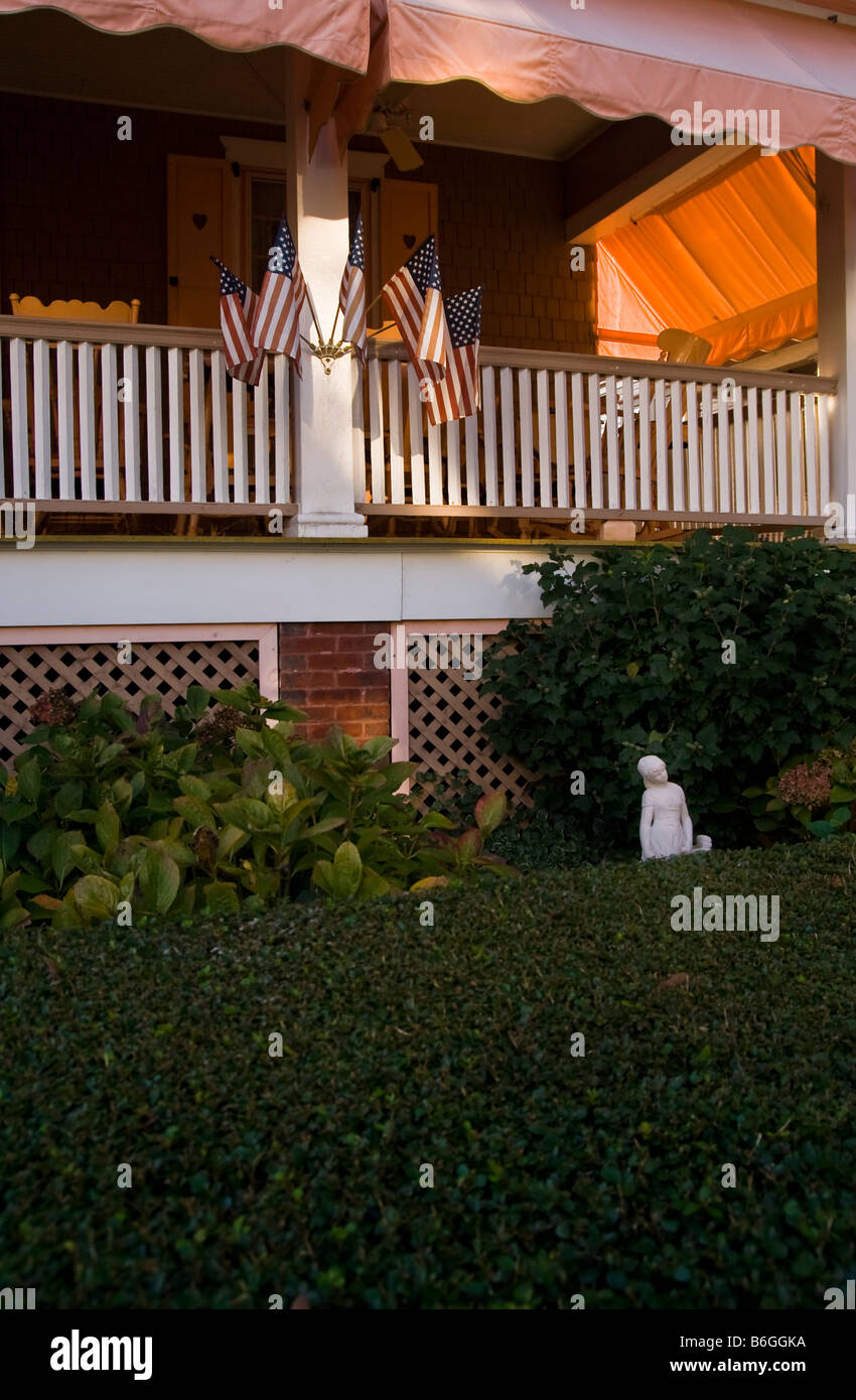 Un porche enveloppant avant et avec une haie taillée, statue et des drapeaux américains. Banque D'Images