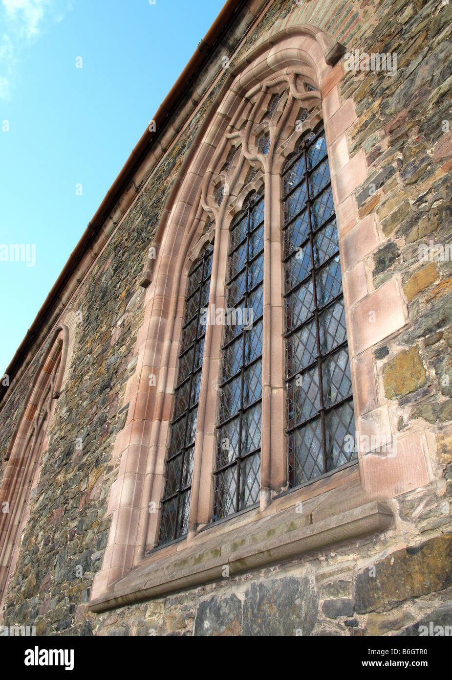 L'église chrétienne à meneaux de pierre arch vitrail avec barres de sécurité. Banque D'Images