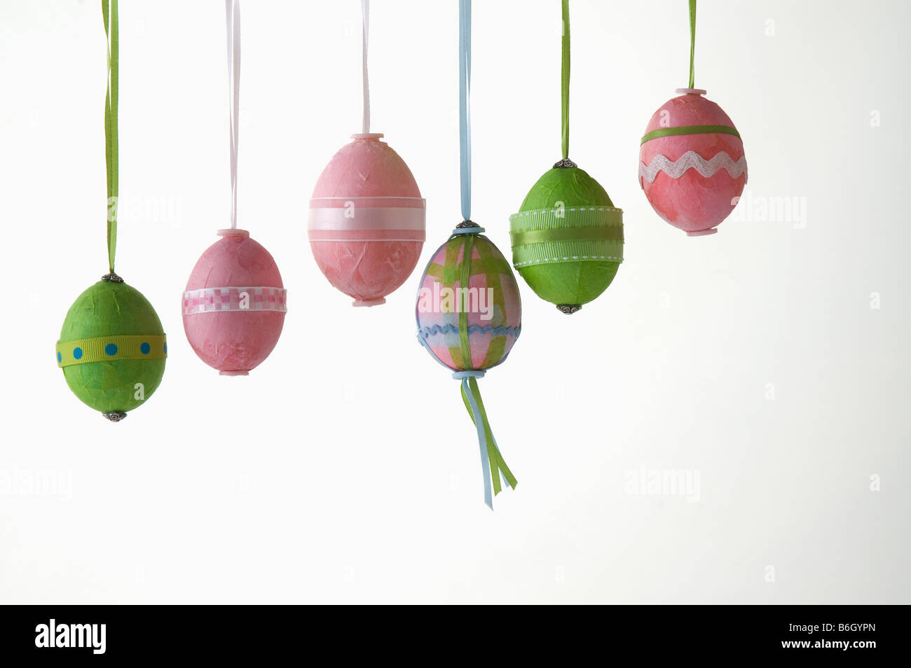 Six oeufs de Pâques colorés colorés suspendus dans une rangée Banque D'Images