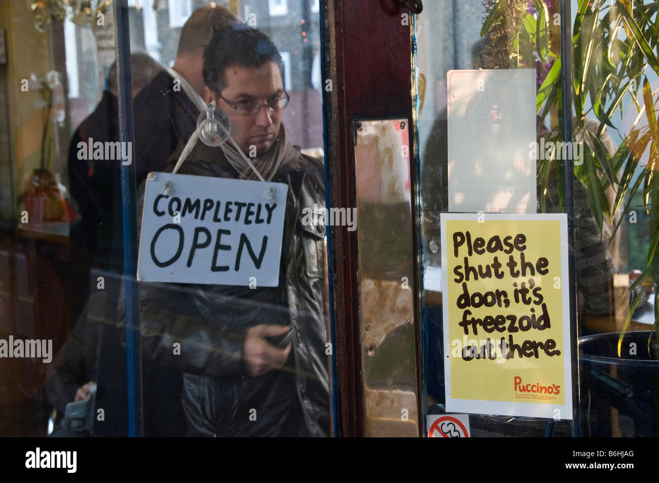 Un homme regardant à travers la porte de verre d'un café de la gare, la gare de Twickenham, London, UK Banque D'Images