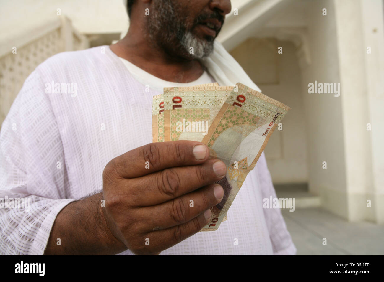Man holding Qatari riyal dix billets, rognées, Doha, Qatar Banque D'Images