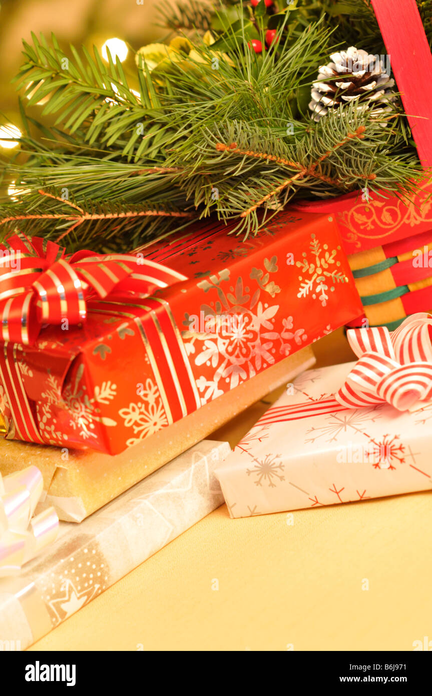 Scène de vacances de Noël avec les cadeaux emballés et décoratifs verts en face de l'arbre de Noël illuminé. Banque D'Images