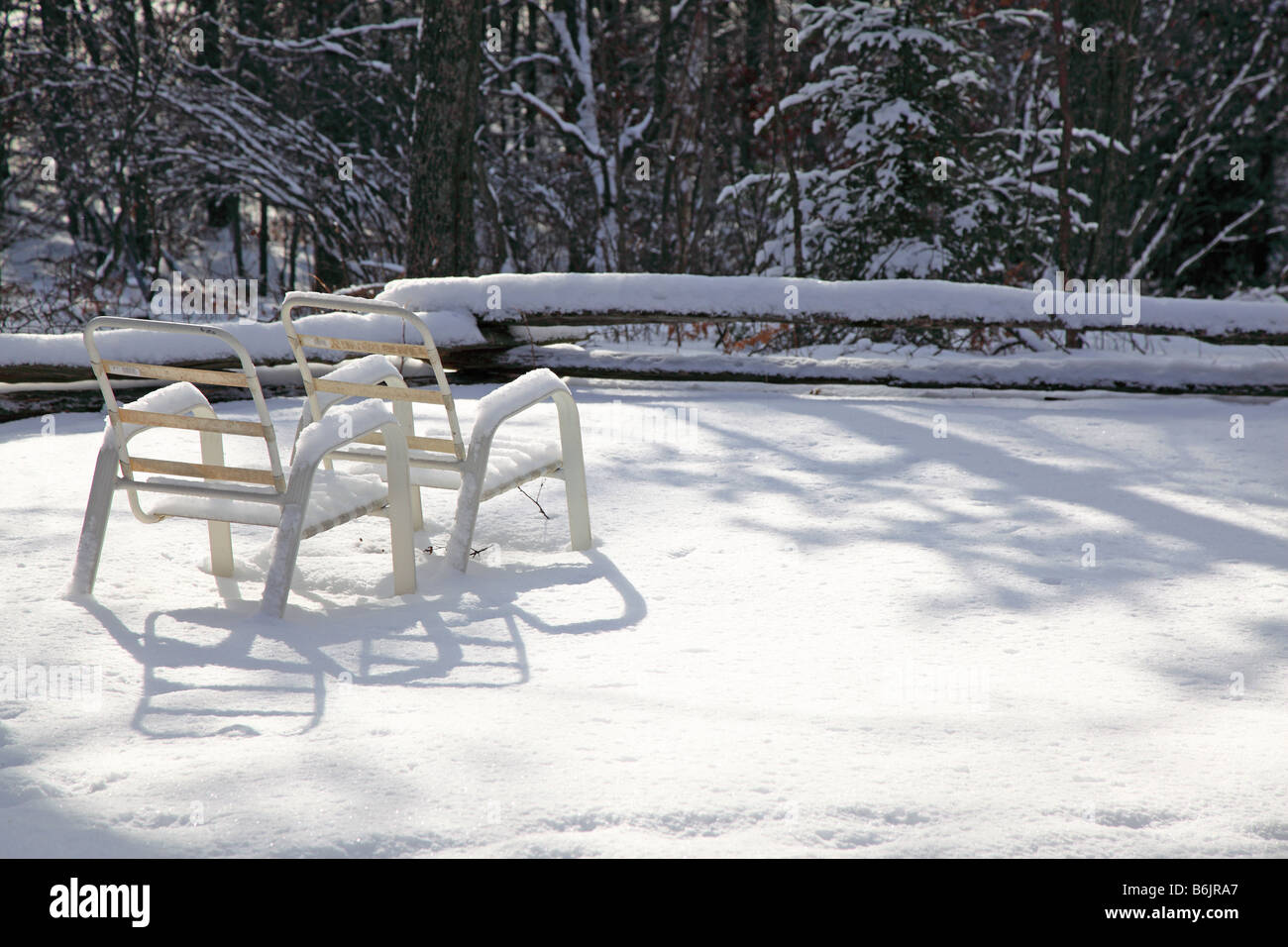 Chaises de salon d'été de gauche à attendre que la neige, maintenant dans la dramatique de longues ombres de fin d'après-midi de décembre & winter snow blanket Banque D'Images