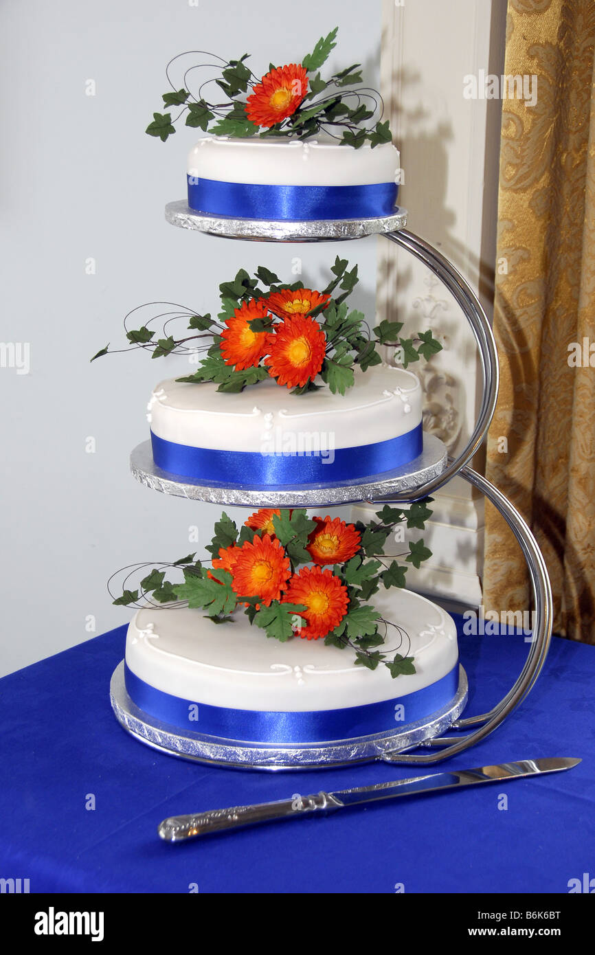 Trois fatigué gâteau de mariage glacé sur stand d'argent décoré de fleurs et feuillage gerbera Banque D'Images