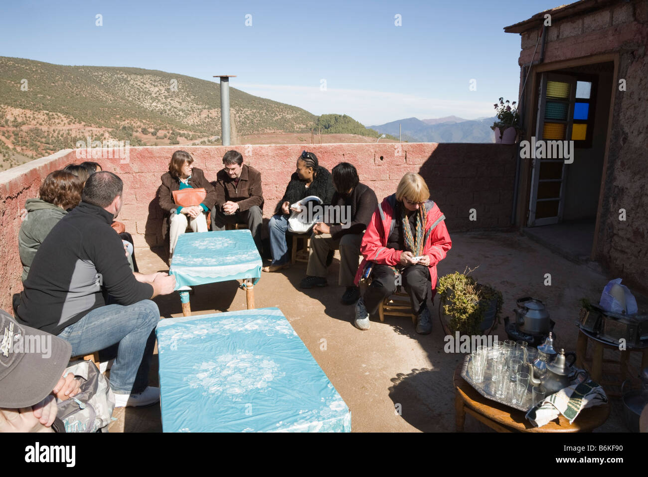 Maroc Sidi Faress Décembre groupe de touristes en attente de thé à la menthe sur toit de maison berbère traditionnelle Banque D'Images