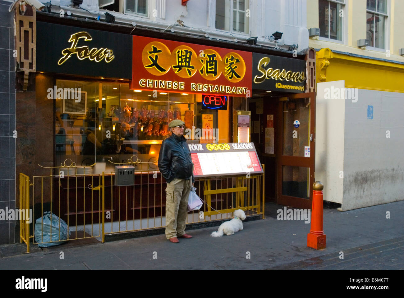 L'homme et un chien en face d'un restaurant dans Gerrard Street dans le quartier chinois dans le centre de Londres, Angleterre, Royaume-Uni Banque D'Images
