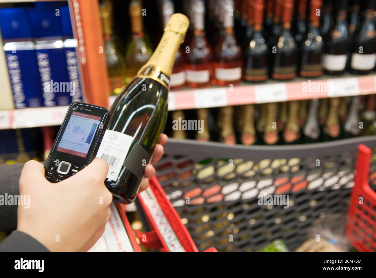 Jeune femme analyse le prix d'une bouteille de champagne dans son téléphone cellulaire dans le véritable avenir stocker une partie de l'avenir du Groupe Metro Banque D'Images