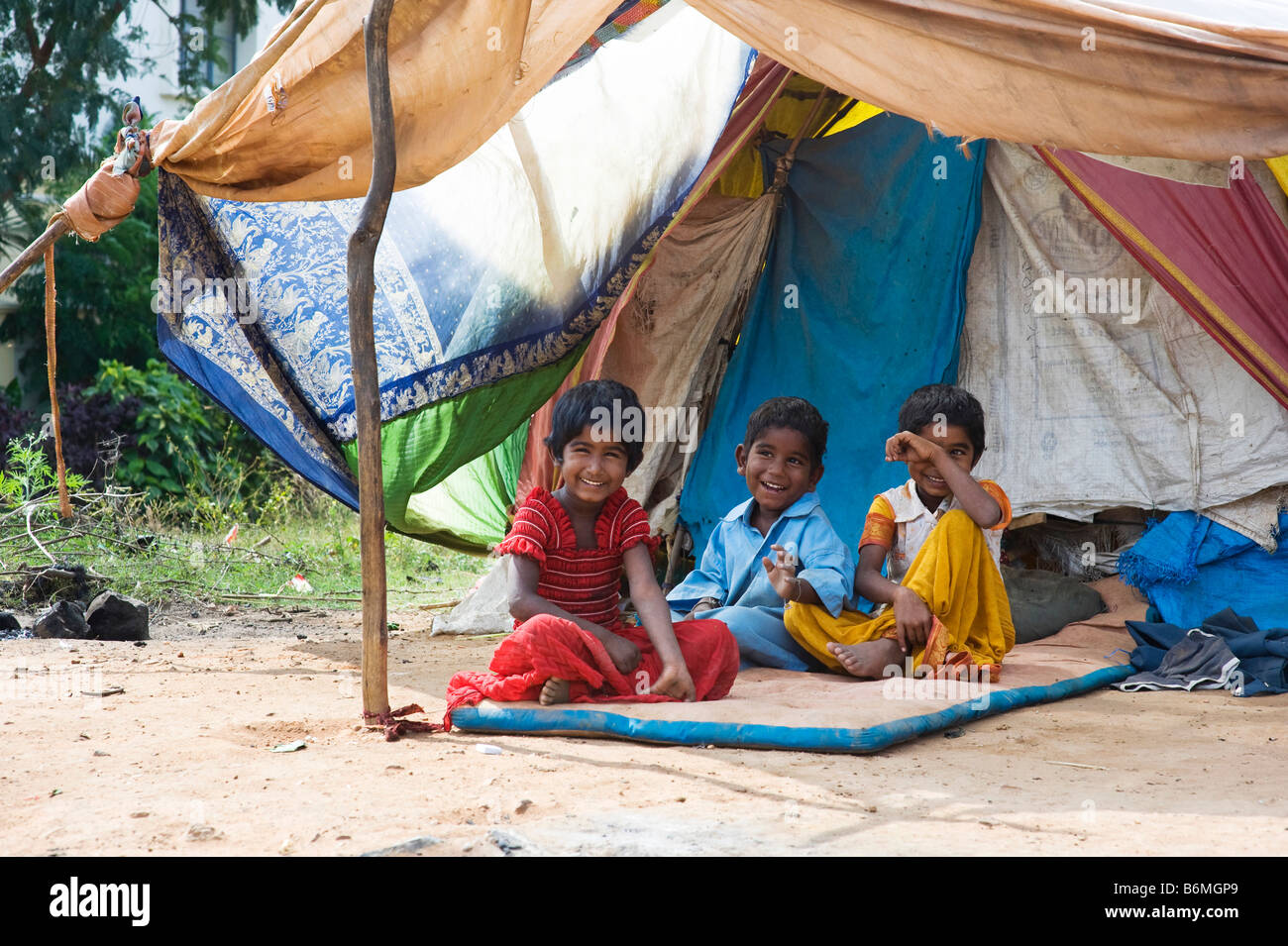 Heureux les pauvres enfants indiens assis à l'extérieur de leur tente à la maison. L'Andhra Pradesh, Inde Banque D'Images