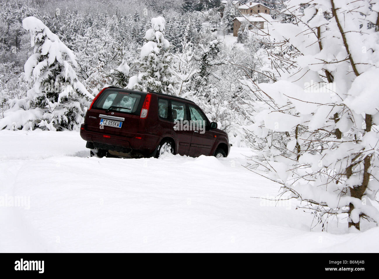 Voiture SUV coincé dans une neige entouré d'arbres couverts de neige fraîche. Banque D'Images