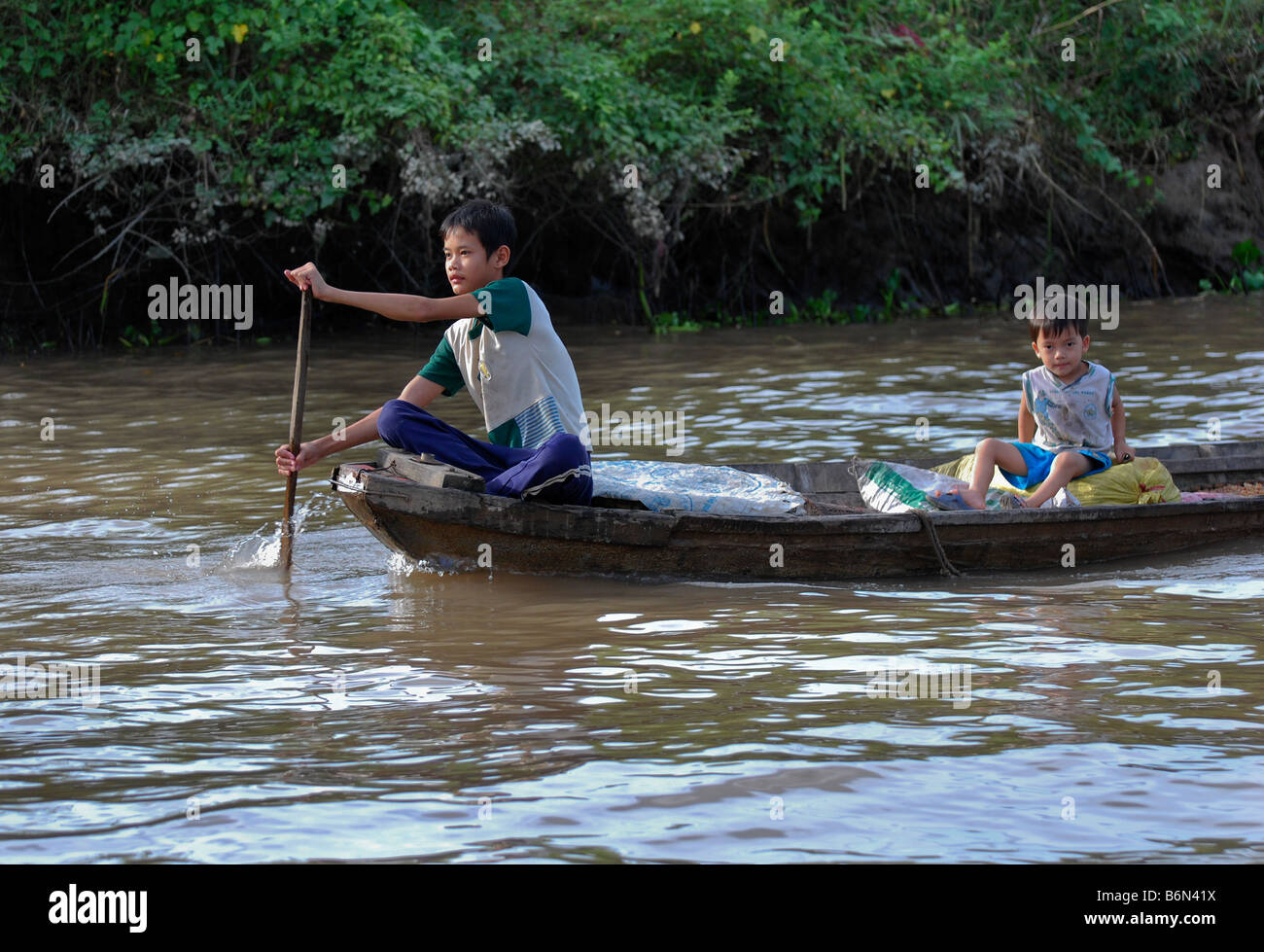 Garçon et tout-petit sampan dans le Delta du Mékong, Vietnam Banque D'Images