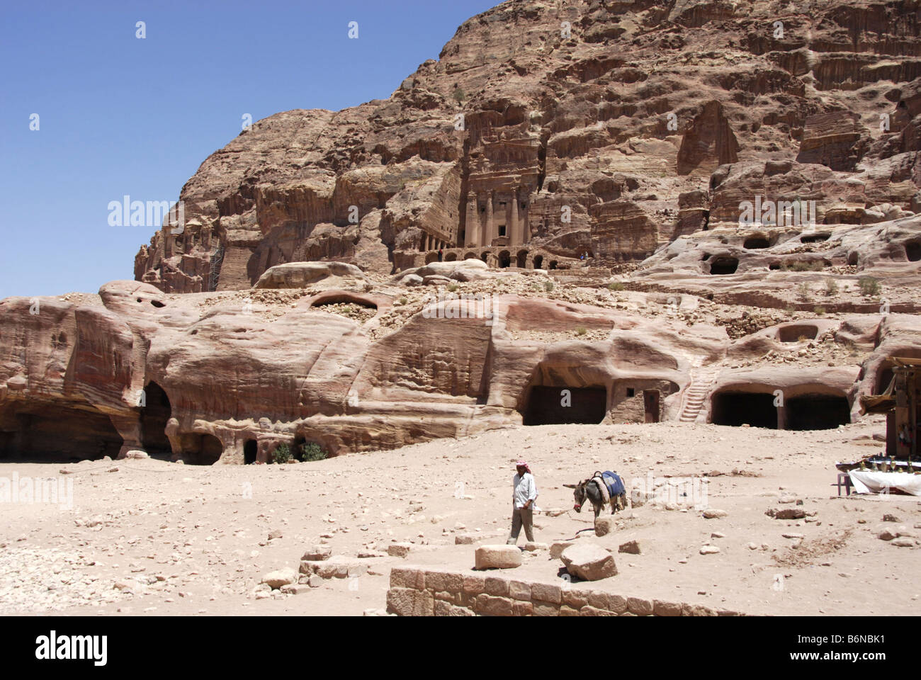 Leader arabe âne en face de bâtiments sculptés sur le côté de la falaise, à Petra, Wadi Musa, Jordan Banque D'Images