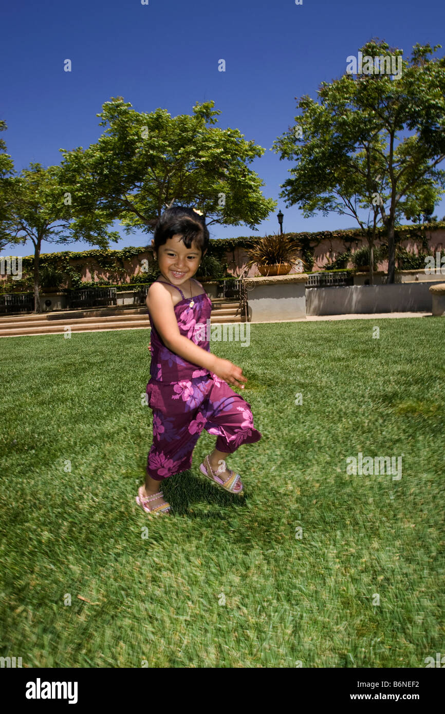 Hispanic girl running on grass Banque D'Images