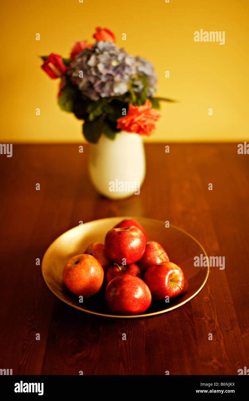 Bol de pommes sur table avec vase de fleurs roses et de l'hortensia Banque D'Images