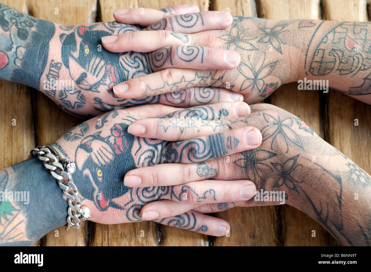 Les mains entrelacées d'un couple marié qui les deux ont des tatouages Banque D'Images