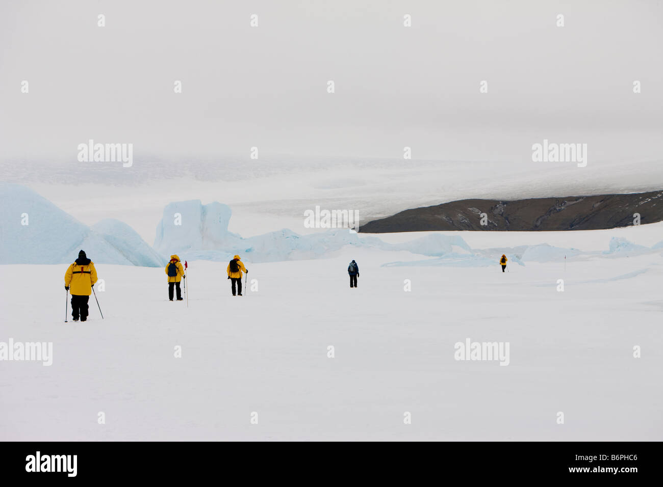 Les touristes d'aventure en jaune manteaux randonnées près de glaciers dans la neige à travers la banquise antarctique sur Snow Hill Island au sud-ouest de l'Antarctique Banque D'Images