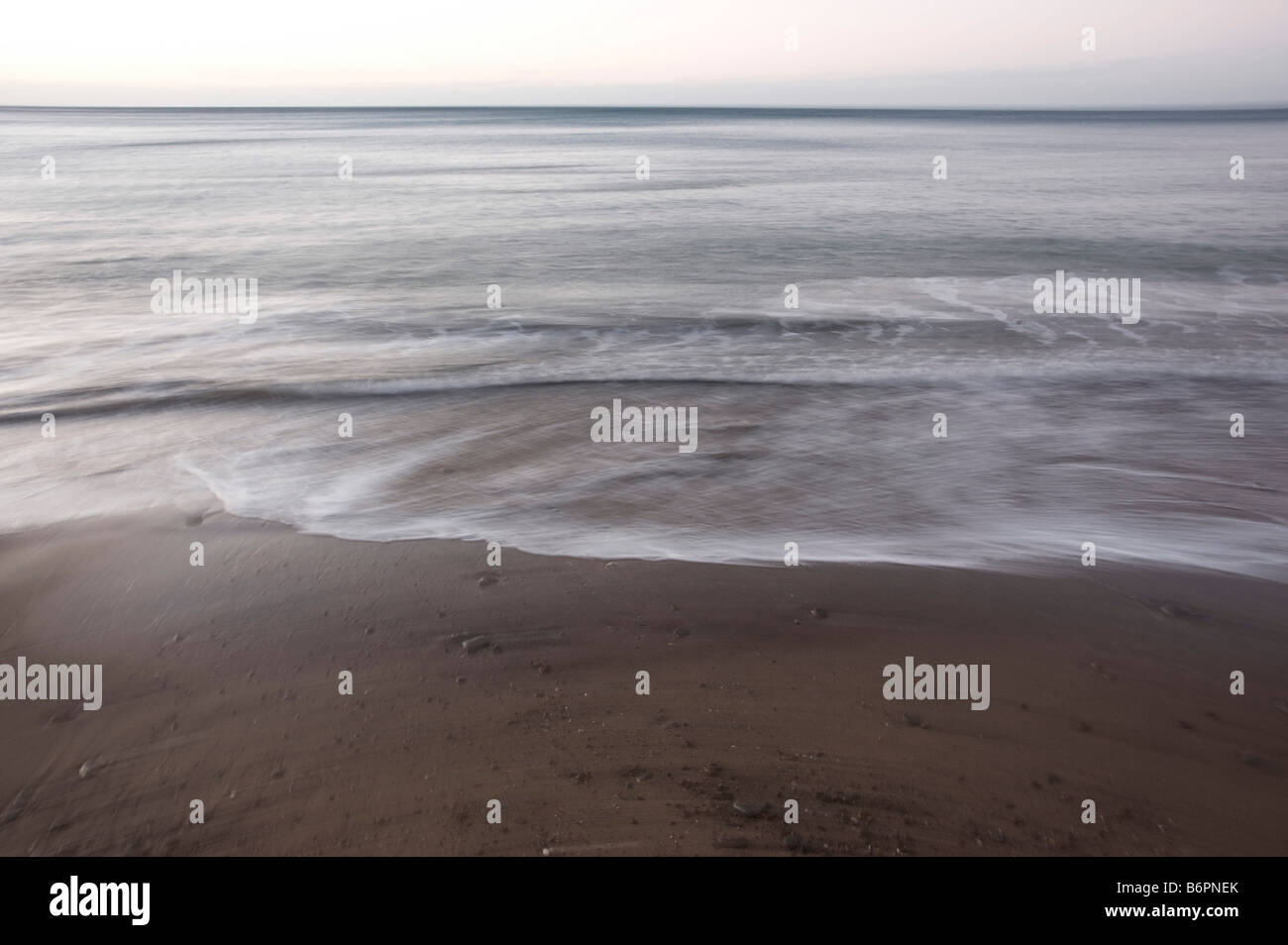 Déménagement des vagues et du sable sur la plage calme Banque D'Images