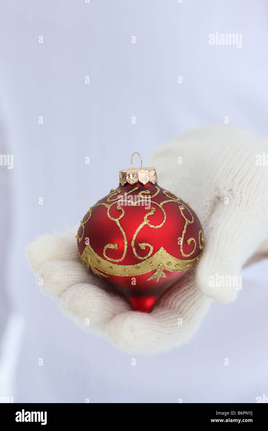 Les mains avec des gants hiver holding Christmas Tree Ornament Banque D'Images