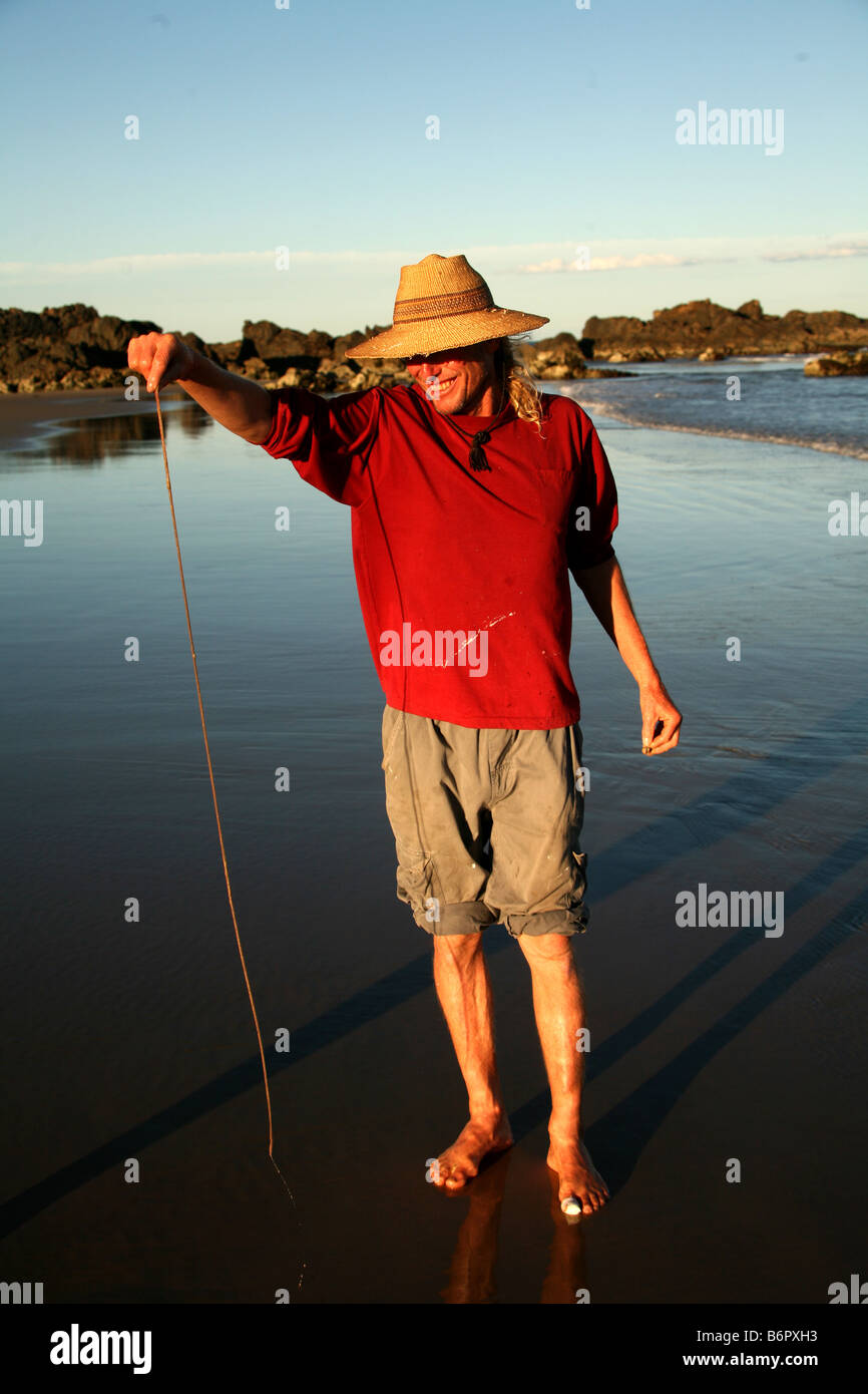 Un pêcheur détient un ver de plage qu'il vient de tirer de la plage Crescent Head près de l'Australie Banque D'Images