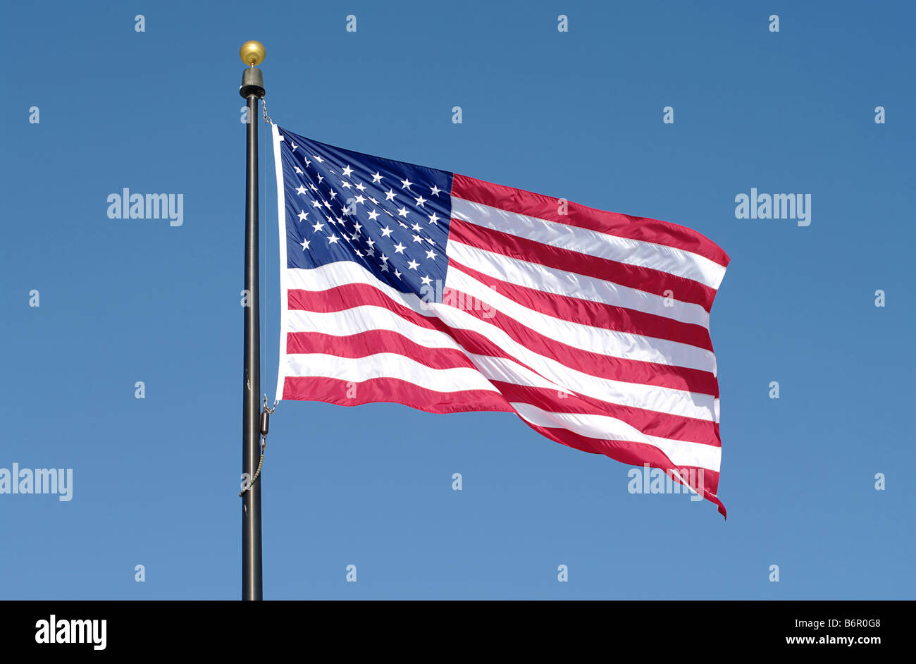 Brandir le drapeau américain contre le ciel bleu Banque D'Images