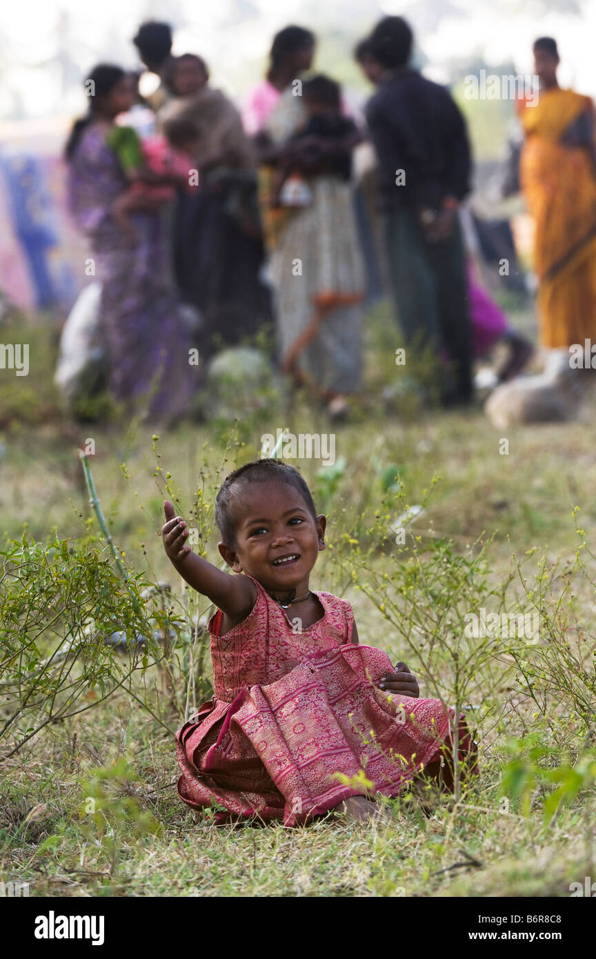 Pauvre petit Indiens nomades basse caste baby girl sitting on l'herbe à l'extérieur du campement de tentes. Focus sélectif. L'Andhra Pradesh, Inde Banque D'Images