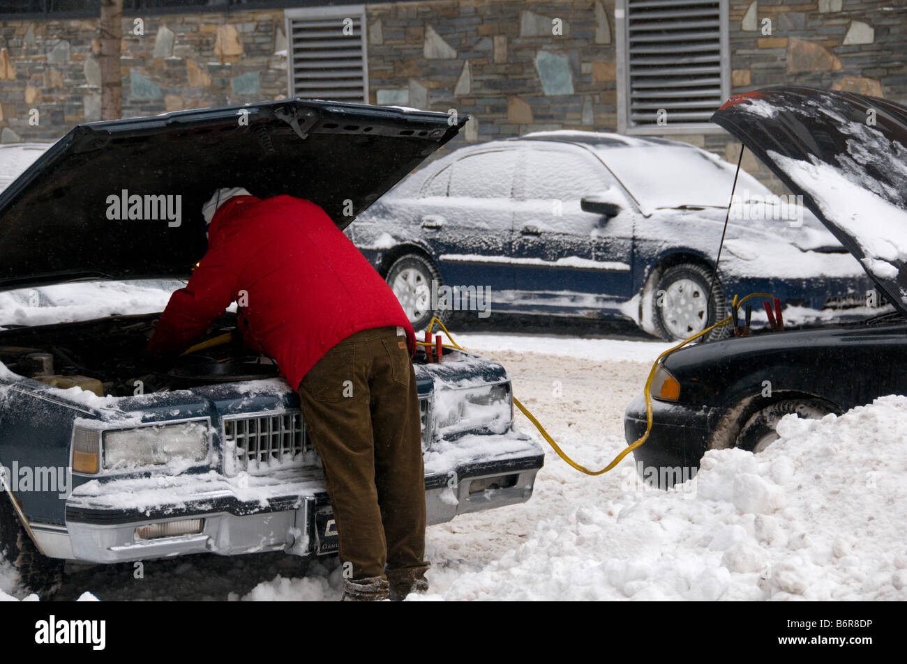 Homme stimuler sa voiture après une tempête Banque D'Images