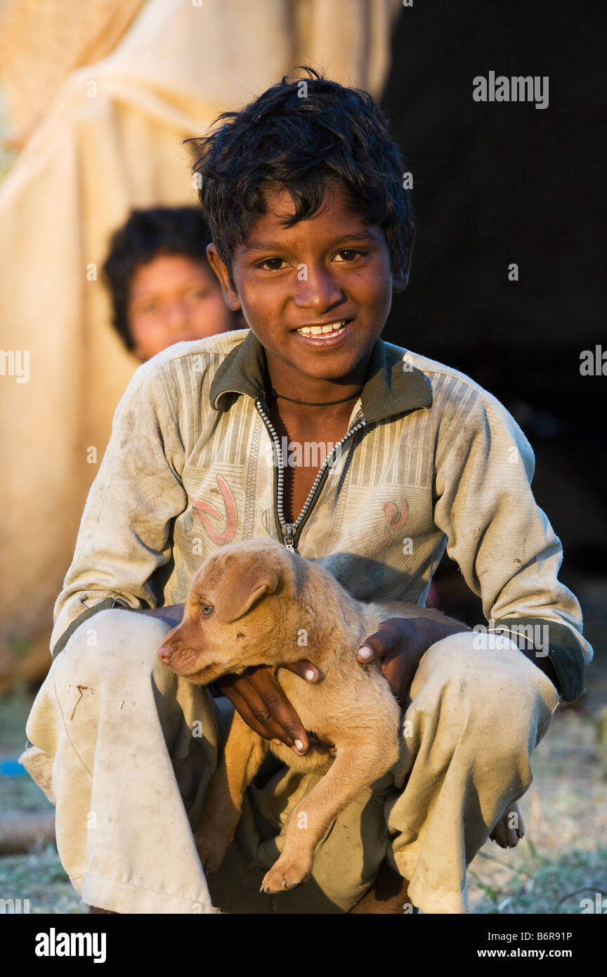 Les Indiens nomades pauvres Garçon jouant avec un petit chien. L'Andhra Pradesh, Inde Banque D'Images