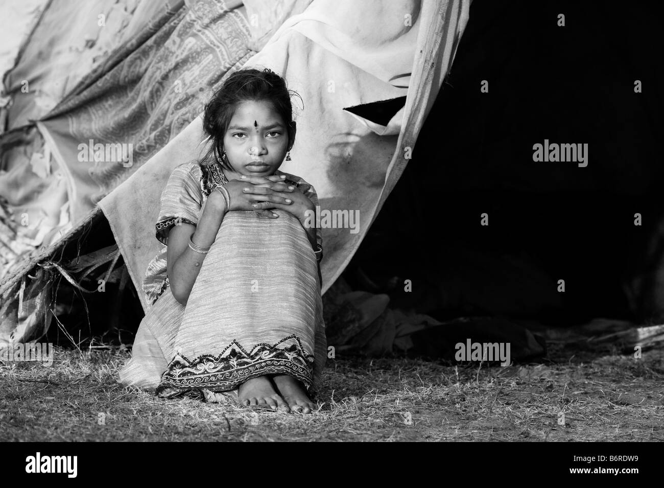 Les pauvres Indiens nomades fille assise devant sa tente. L'Andhra Pradesh, Inde. Le noir et blanc Banque D'Images