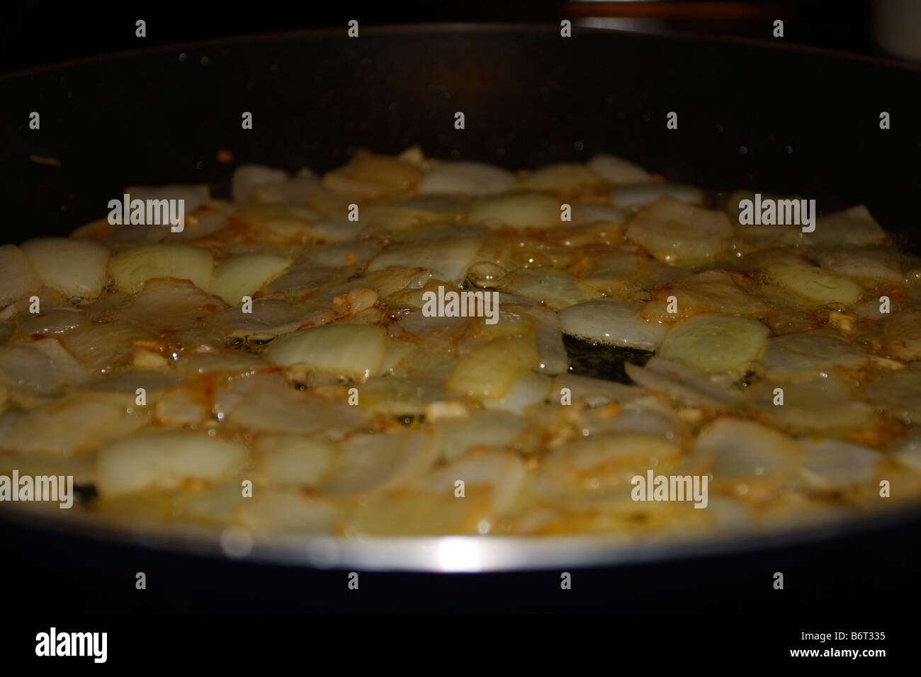 Caraméliser les oignons dans la poêle. Banque D'Images