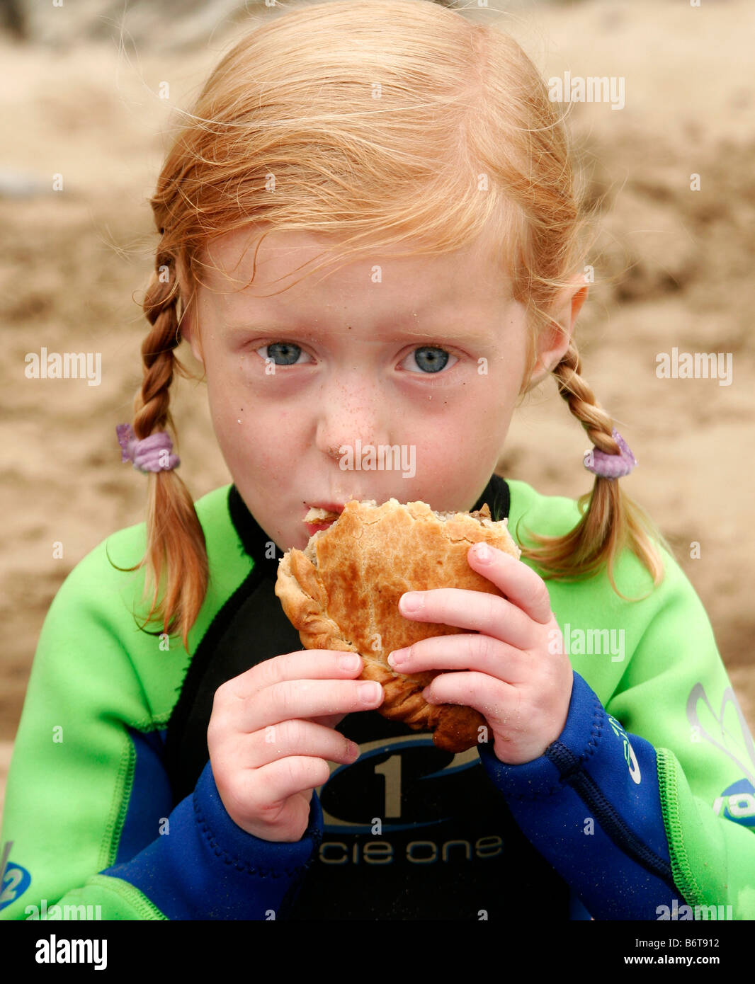 Young Girl eating a Cornish Pasty traditionnel sur la plage à Cornwall Banque D'Images