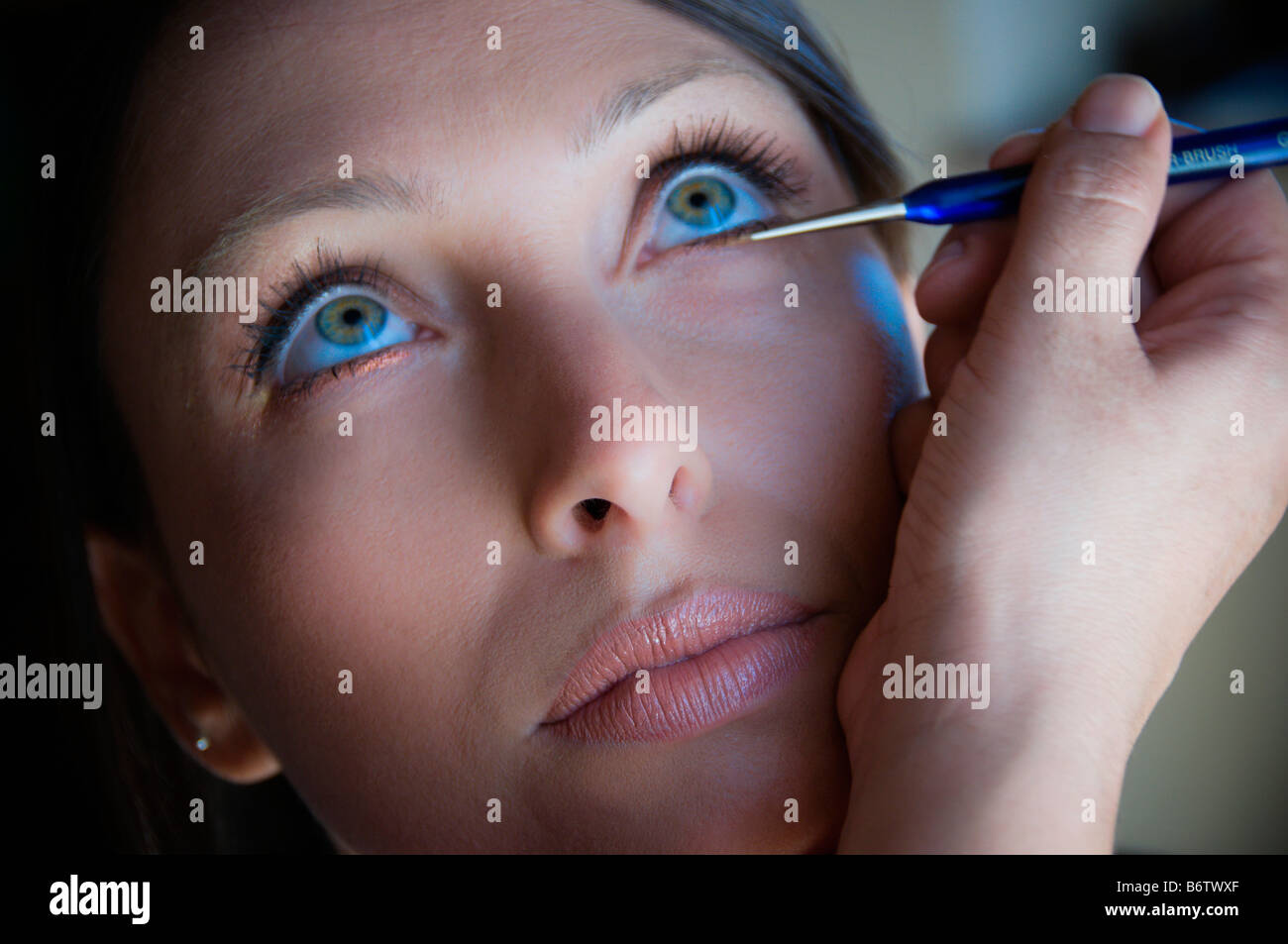 Woman applying eyeliner Banque D'Images