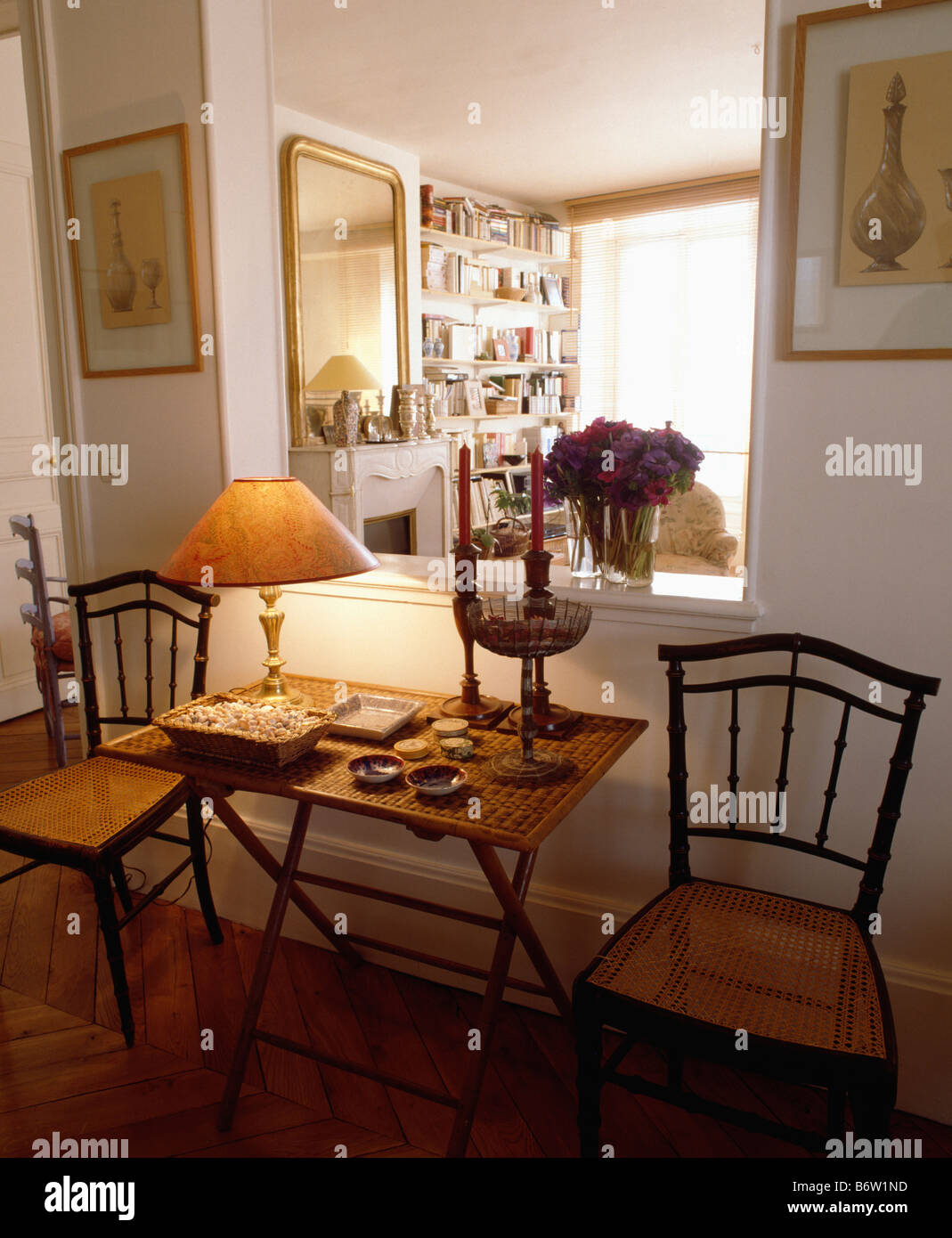 Chaises anciennes de chaque côté d'une petite table avec lampe allumée en  face d'espace ouvert dans le mur entre hall et salle de séjour Photo Stock  - Alamy