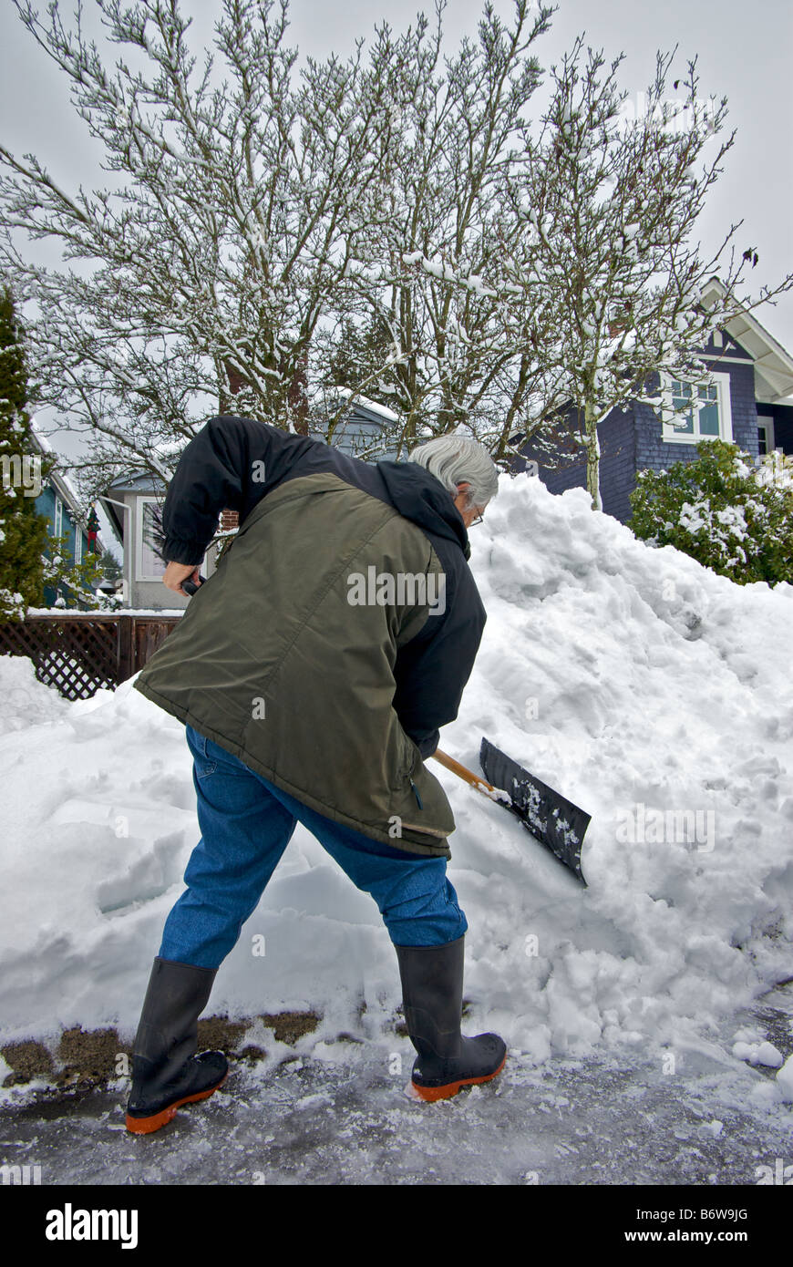 À l'aide de l'homme position genou plié pour creuser la neige à partir de l'espace de stationnement sur le côté rue après la grande tempête Banque D'Images