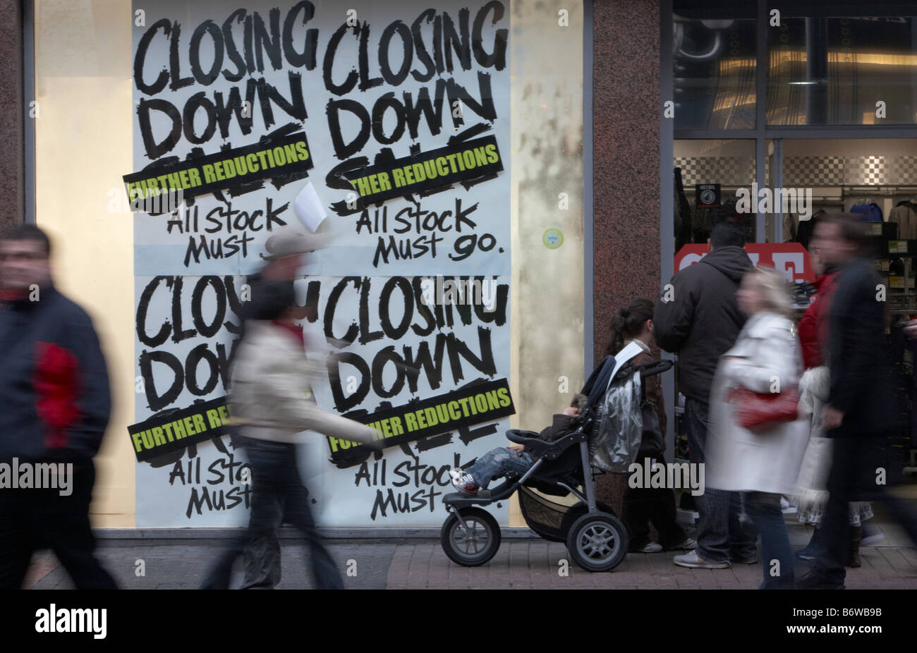 Les consommateurs et les familles en passant devant l'arrêt des signes de vente dans une vitrine dans le Royaume-Uni Banque D'Images