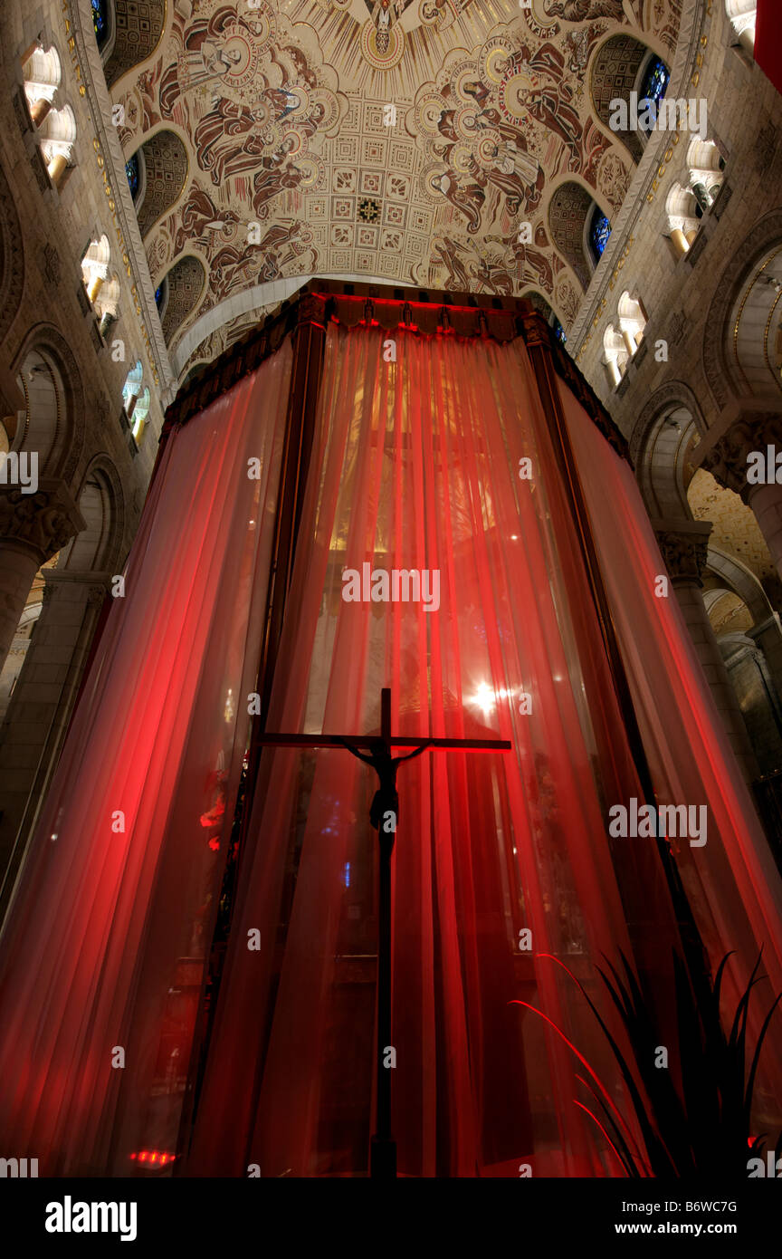 Une statue de Jésus sur la croix qui se profile contre un rideau rouge dans une église Banque D'Images