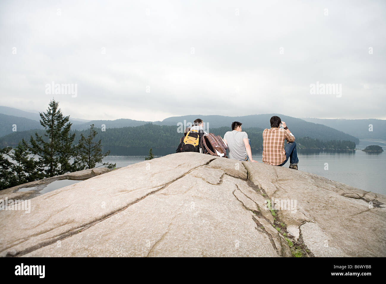 Les gens sur la roche par un lac Banque D'Images