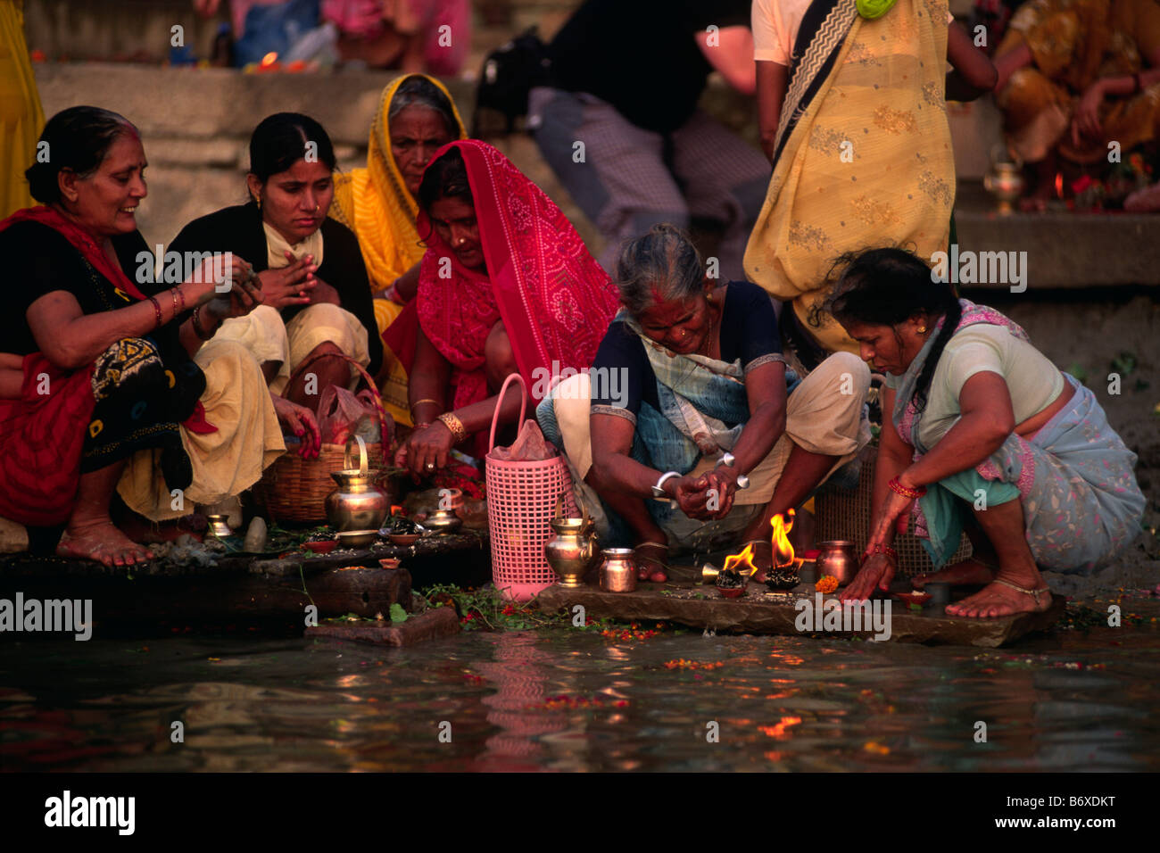 Inde, Varanasi, fleuve Gange, femmes donnant des offrandes à l'aube Banque D'Images