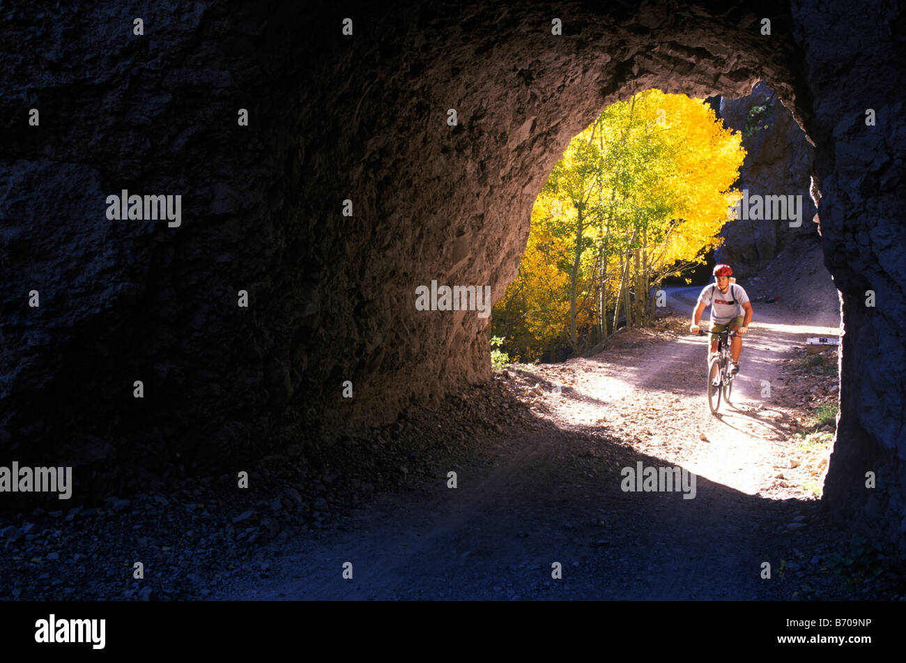 Un jeune homme ses pédales vtt tremble à l'âge d'or et les feuilles dans un tunnel de roche alors que le vélo de montagne dans le San Francisco Banque D'Images