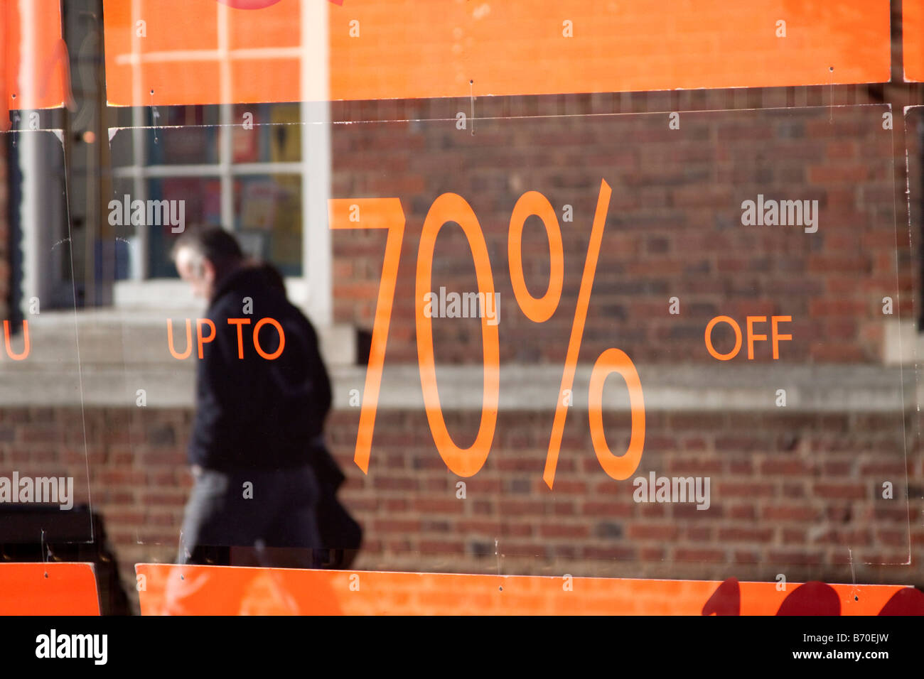 ORANGE 70  % SUR VENTE SIGNES EN VITRINE À LA RÉFLEXION DES ACHETEURS EN PASSANT DEVANT À L'ARRIÈRE-PLAN Banque D'Images