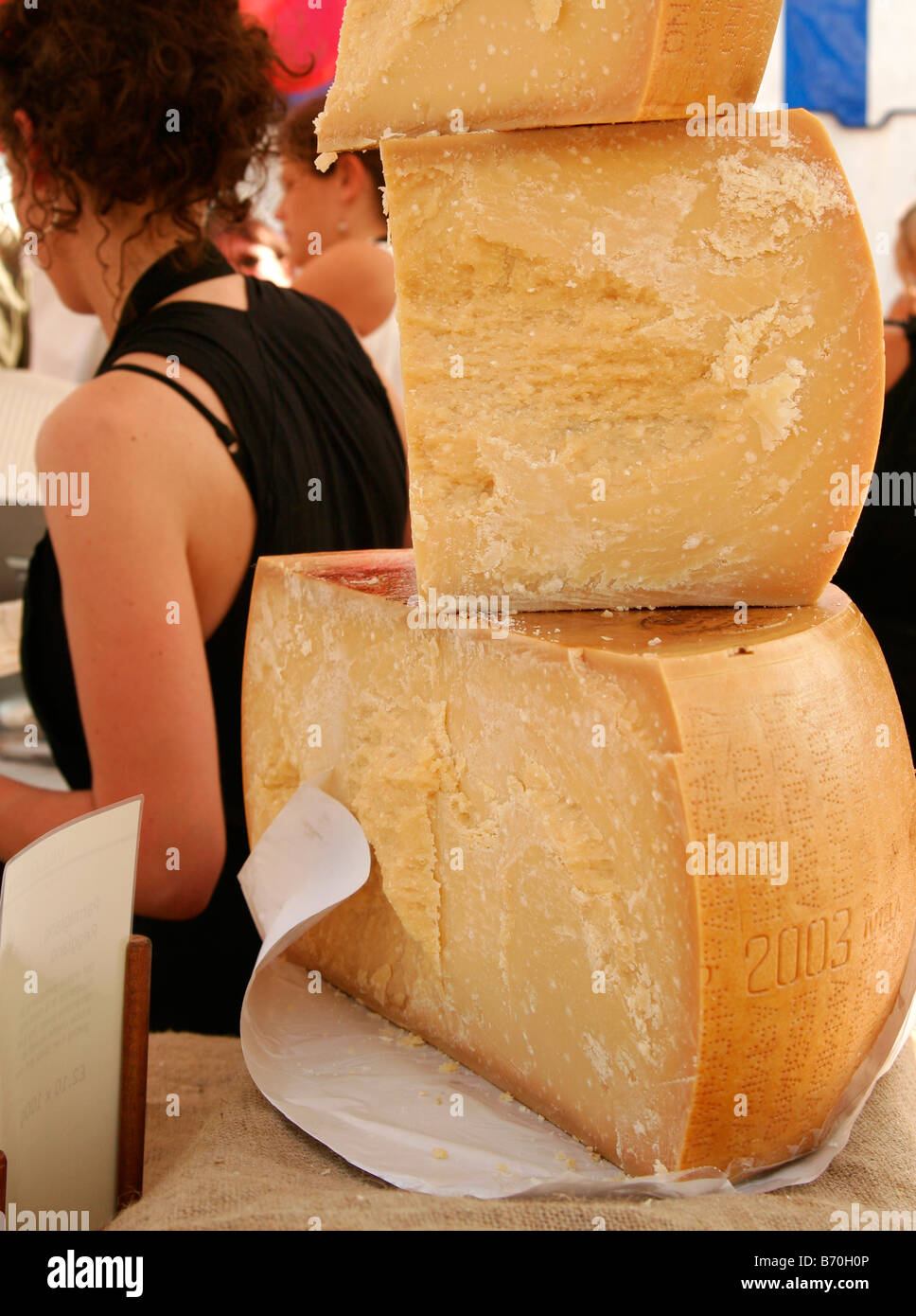 Pile de morceaux de Parmigiano Reggiano Bio avec du fromage Monger dans l'arrière-plan au Festival des aliments biologiques à Bristol Banque D'Images