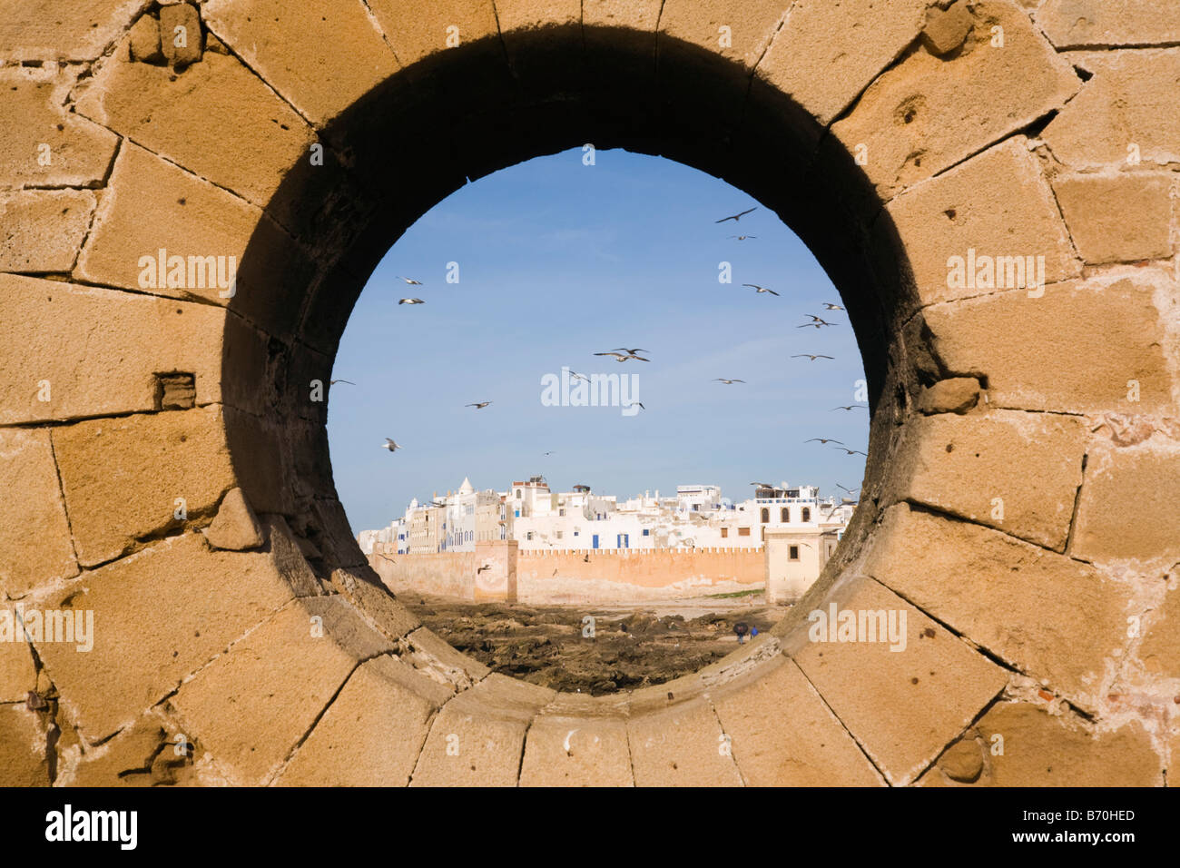 Essaouira Maroc Afrique du Nord Vue d'immeubles blancs à Medina ville du 18ème siècle à travers le trou dans le mur des remparts circulaires Banque D'Images