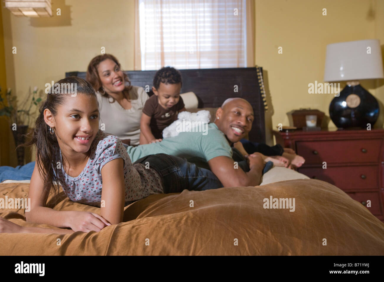 Happy African American family lying on bed watching TV Banque D'Images