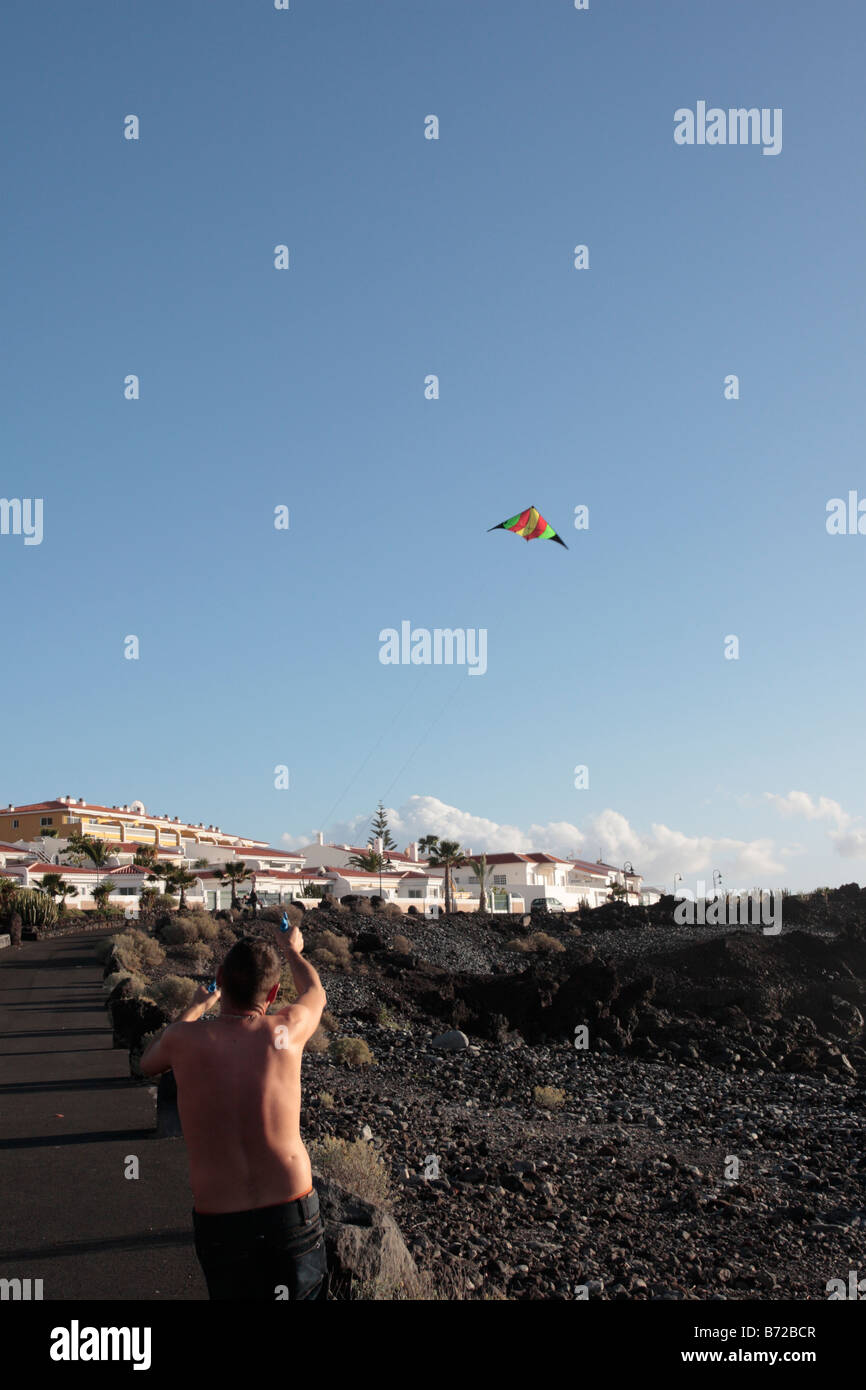 Un garçon flys un cerf-volant dans un ciel bleu clair par la côte à Playa San Juan Tenerife Espagne Banque D'Images