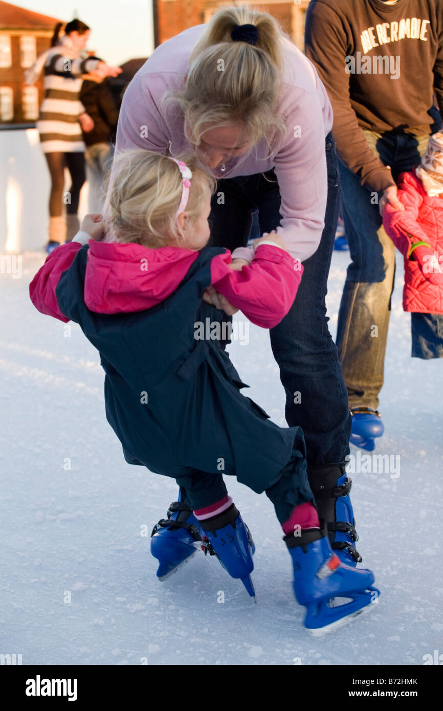 Femme tenant sa fille, alors qu'il patine apprendre à patiner, à Hampton Court Palace Ice Rink. Le Palais de Hampton Court. UK. Banque D'Images